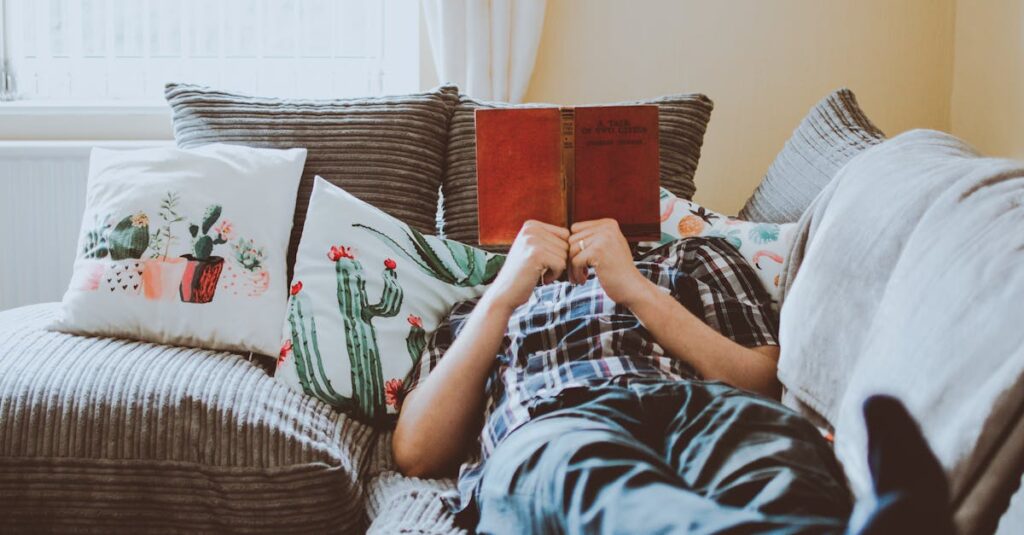 ๐ 5 Lifestyle Essentials Every Book Lover Needs Relaxing at home, lying on a sofa with a book and cushions around.